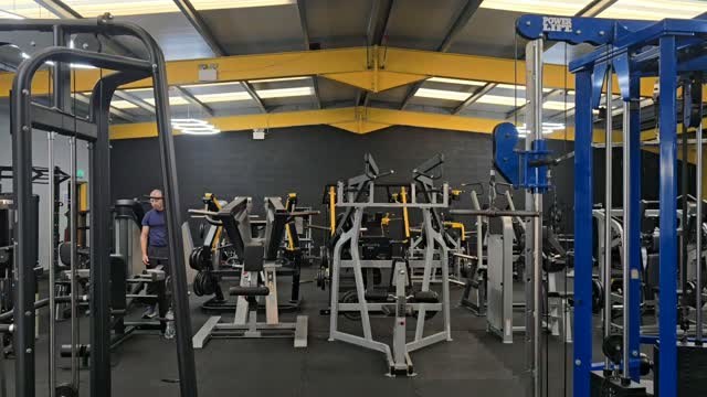 Rows of plate-loaded machines and racks under yellow steel beams